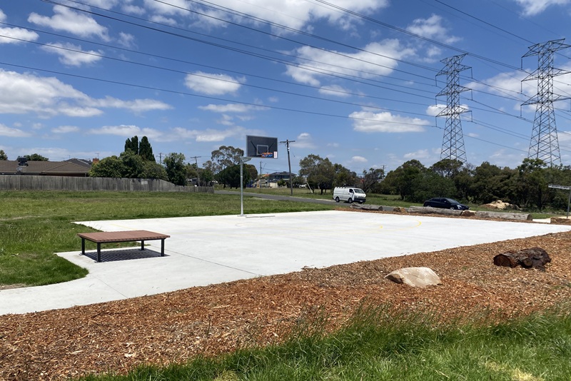 Concrete basketball halfcourt area with adjacent seating.