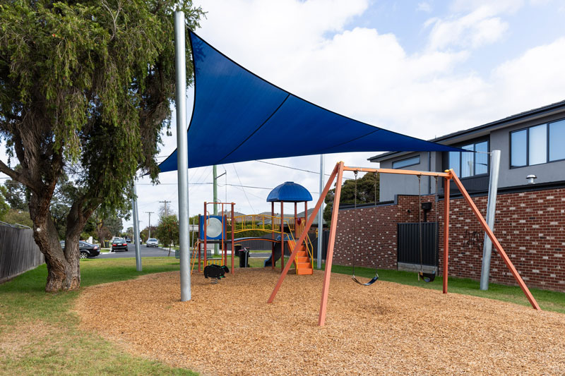 Children's playground including swing set and climbing structure.