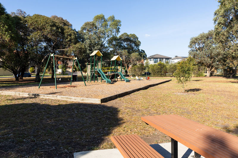 A view of the park with children's playground and table set.